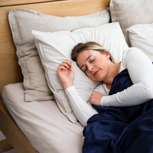 Vrouw slaapt ontspannen in een opgemaakt bed met zachte kussens en een warm dekbed